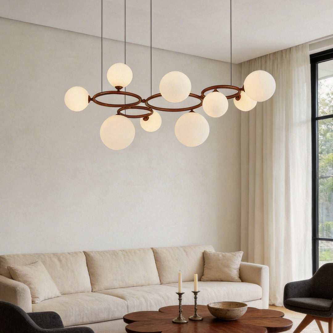 Opal glass globes on a slim ring glowing softly above a cream sofa and a round wooden coffee table