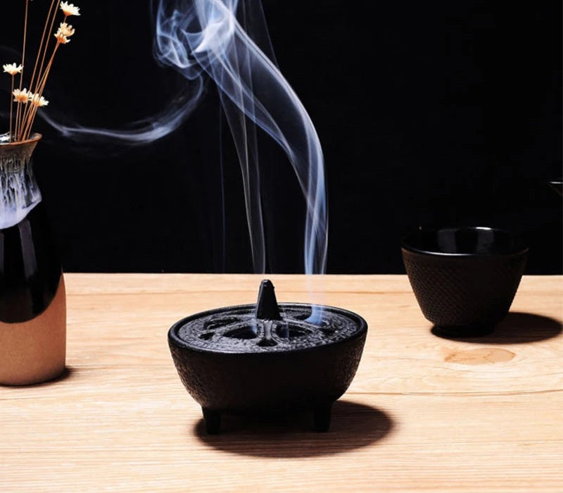 Mini cast iron incense censer burning on a wooden table