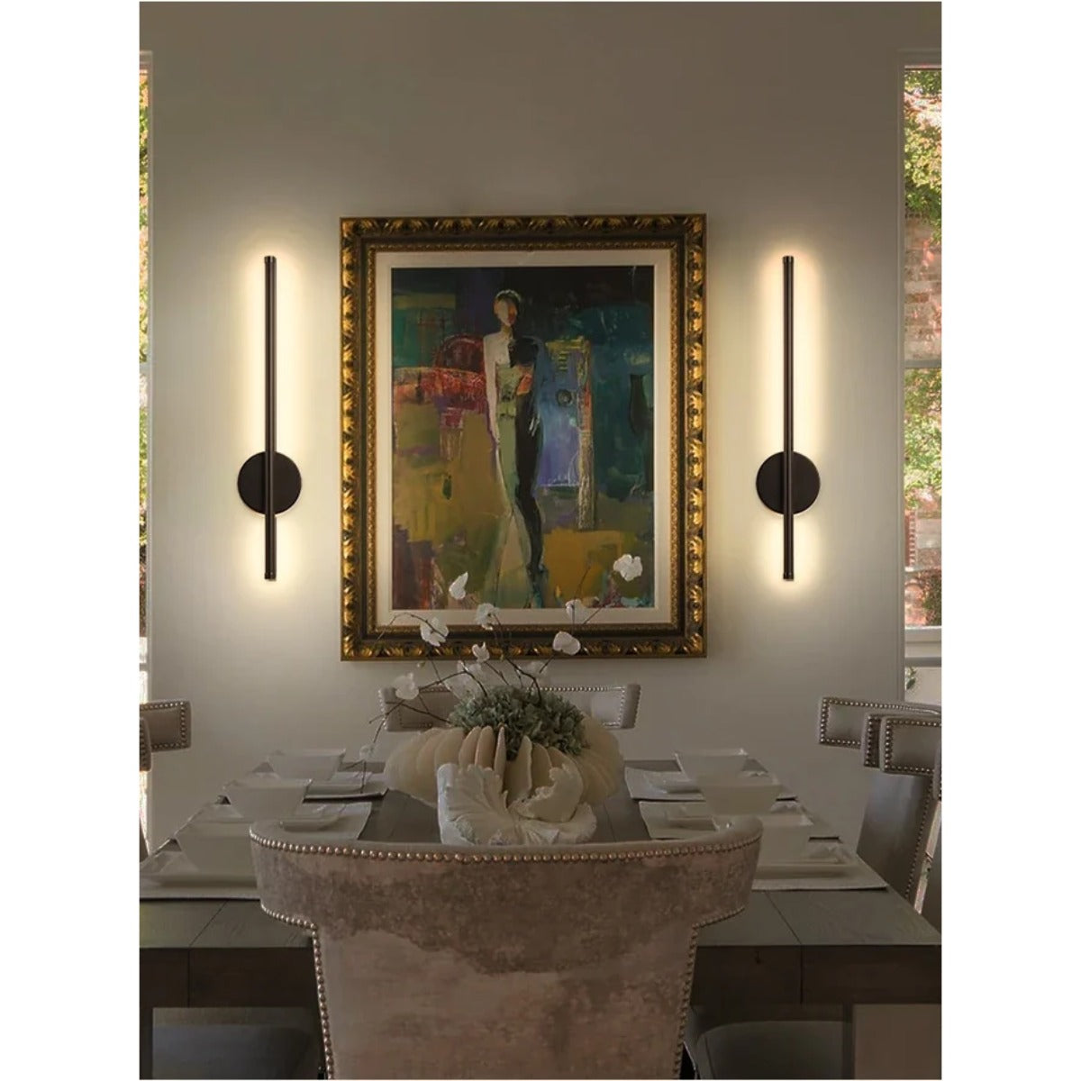 Wall sconces framing artwork in dining room