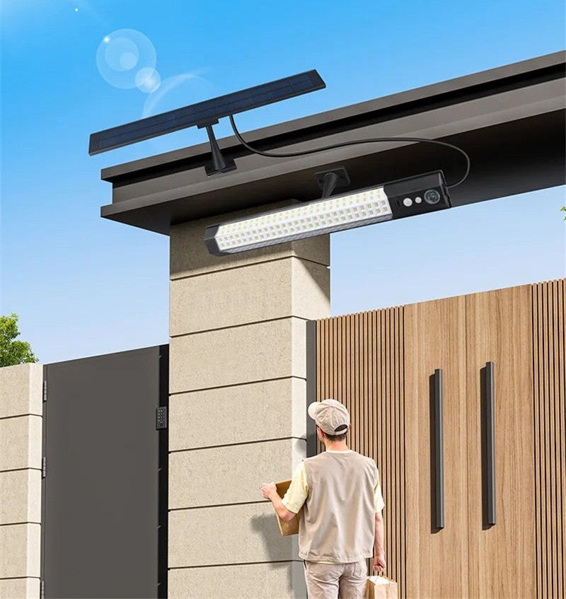 Solar wall lamp with roof-mounted panel over a gate entrance
