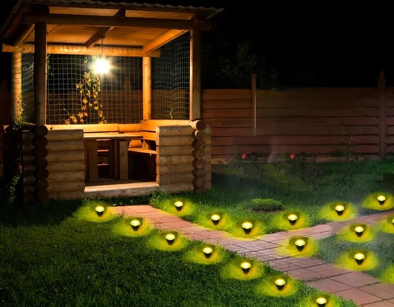 Solar garden lights lighting a backyard path by a wooden gazebo