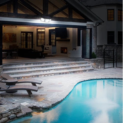 Solar flood light over a backyard pool at night