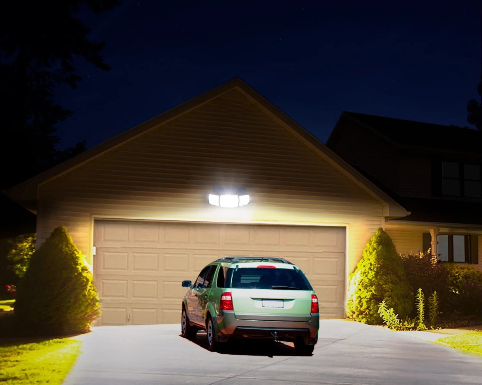 Solar flood light lighting a driveway and garage at night