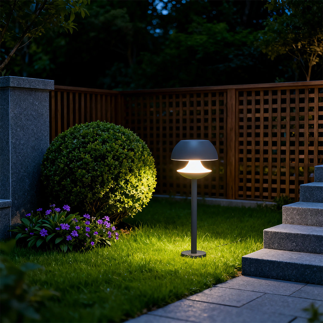 Garden path at dusk lit by mushroom path lights beside low shrubs